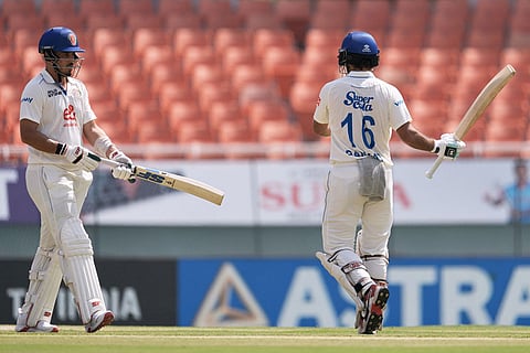 Afghanistan's Sharafuddin Ashraf, left, walks toward batting partner Rahmat Shah as the latter celebrates his fifty runs on day three of the cricket test match between Afghanistan and India in New Chandigarh, India.