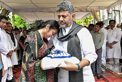 Karnataka CM DK Shivakumar presents the national flag to a family member of late AICC secretary Suraj Hegde during the latter’s funeral, in Bengaluru.