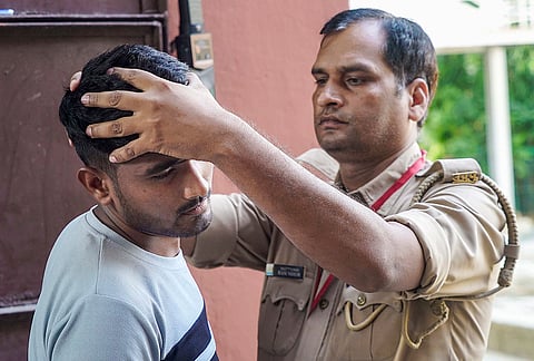 An aspirant undergoes security checks before appearing for the 'Uttar Pradesh Police constable recruitment examination', in Varanasi, Uttar Pradesh.