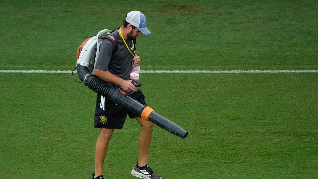 A groundskeeper uses a leaf blower to dry parts of the pitch after a heavy rain before an international friendly soccer match between Costa Rica and England. - AP Photo