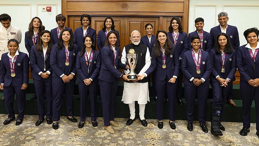Prime Minister Narendra Modi holding the ICC Women's Cricket World Cup winner's trophy as he poses for a photograph with the winning Indian women cricket team in New Delhi.  - | Photo: Handout via PTI 