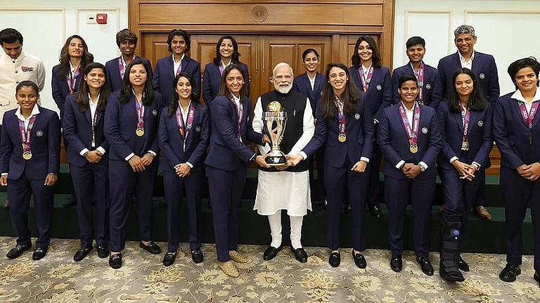 Prime Minister Narendra Modi holding the ICC Women's Cricket World Cup winner's trophy as he poses for a photograph with the winning Indian women cricket team in New Delhi. - | Photo: Handout via PTI