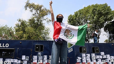 A demonstrator holds a Mexican flag during a march before the opening day of the 2026 FIFA World Cup in Mexico City, Thursday, June 11, 2026. 