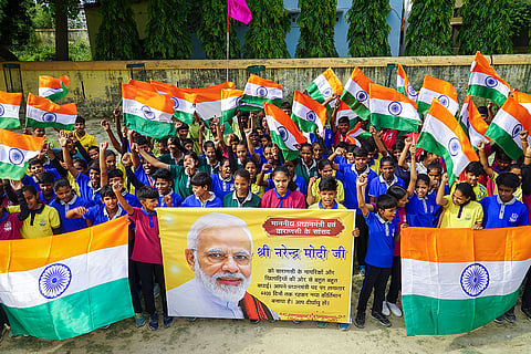 Children wave the national flag and hold a poster of Prime Minister Narendra Modi on the latter’s becoming India's longest-serving elected prime minister, in Varanasi.