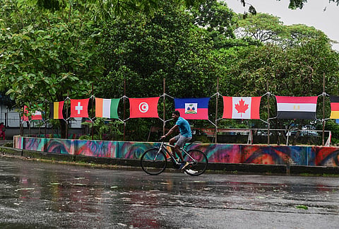 A cyclist pedals through a traffic circle decorated with flags of soccer World Cup teams during monsoon rains in Kochi, southern Kerala state.
