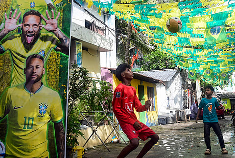 Young boys play football in a street decorated with Brazilian flags and a large poster of footballer Neymar Jr ahead of FIFA World Cup 2026, in Thiruvananthapuram.