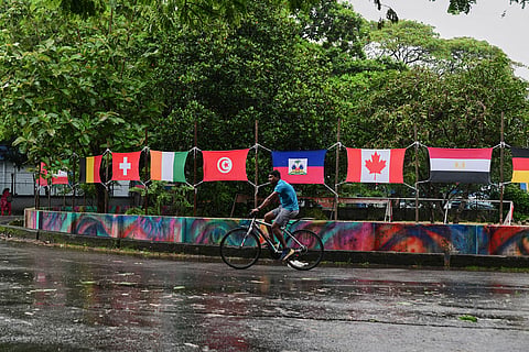 A cyclist pedals through a traffic circle decorated with flags of soccer World Cup teams during monsoon rains in Kochi, southern Kerala state, India.