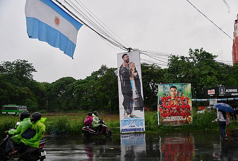 Commuters ride past signages put up by soccer World Cup fans during monsoon rains in Kochi, southern Kerala state. 