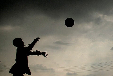 A child plays as clouds hover over the city after rainfall, in Gurugram, Haryana.