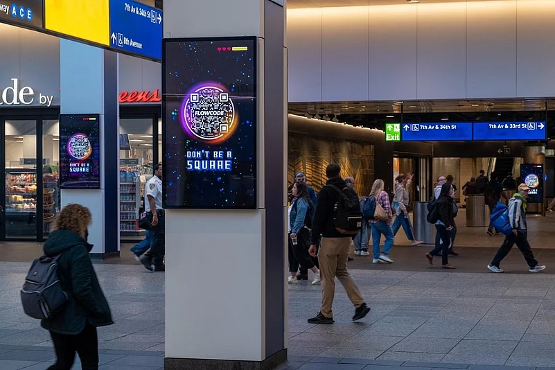 People walking through a modern transit station with a digital advertising display.