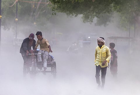 People walk amid a dust storm, in Prayagraj, Uttar Pradesh.