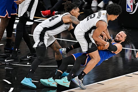 New York Knicks guard Jalen Brunson falls as he pressured by San Antonio Spurs guard Dylan Harper (2) and guard Devin Vassell during the second half of Game 5 of the NBA Finals basketball series in San Antonio.