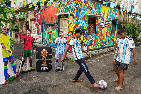 Boys play football near FIFA World Cup 2026-themed murals and cut-outs of Brazil's Neymar, Portugal's Cristiano Ronaldo and Argentina's Lionel Messi, in Kolkata.