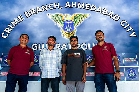 Personnel of the Ahmedabad Crime Branch with two accused arrested for allegedly luring students through Telegram groups with promises of arranging the NEET re-examination paper, at the Crime Branch office in Ahmedabad. The accused were arrested from Rajasthan's Kota district.