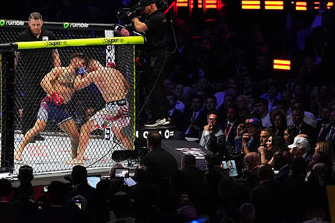 President Donald Trump, at right wearing a white hat, watches the final fight, a lightweight title bout between Ilia Topuria and Justin Gaethje, during UFC Freedom 250 on the South Lawn of the White House in Washington.