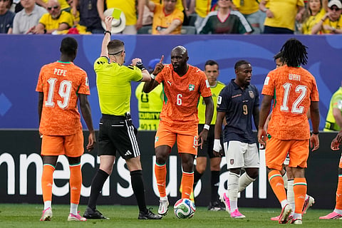 Referee François Letexier of France books Ivory Coast's Seko Fofana during a World Cup Group E soccer match against Ecuador in Philadelphia, Sunday, June 14, 2026.