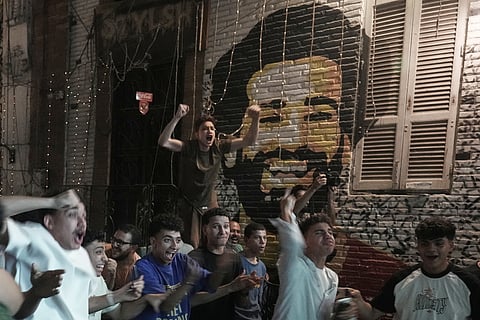 Fans celebrate after Egypt scored the first goal as they watch a broadcast of the World Cup soccer match between Egypt and Belgium at a coffee shop in Cairo, Egypt, Monday, June 15, 2026. Background a graffiti shows Egypt soccer star Mohamed Salah.