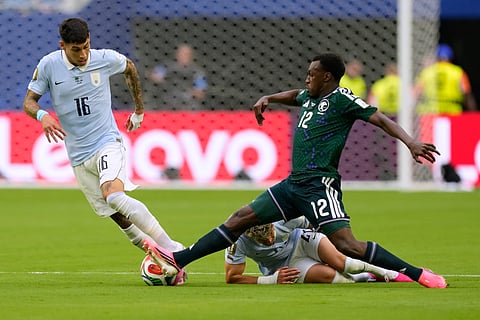 Saudi Arabia's Saud Abdulhamid (12) and Uruguay's Mathias Olivera fight for the ball during a World Cup Group H soccer match in Miami Gardens, Fla., Monday, June 15, 2026.