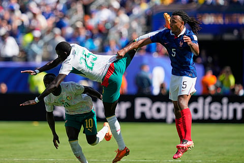 France's Jules Kounde holds on to the shirt of Senegal's El Hadji Malick Diouf during the World Cup Group I soccer match between France and Senegal in East Rutherford, N.J., near New York, Tuesday, June 16, 2026.
