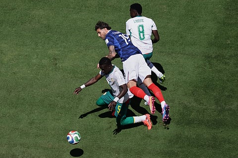 France's Theo Hernandez falls between Senegal's Idrissa Gana Gueye and Lamine Camara during the World Cup Group I soccer match between France and Senegal in East Rutherford, N.J., near New York, Tuesday, June 16, 2026.