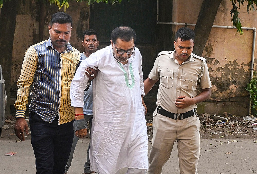 Police personnel escort former West Bengal minister and Trinamool Congress (TMC) leader Ujjal Biswas to a district court following his arrest in connection with an alleged relief materials misappropriation case, in Nadia district, West Bengal. - | Photo: PTI