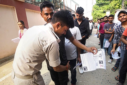 Security personnel check candidates before they enter an examination centre for the CSBC Bihar Prohibition Constable examination, in Patna.