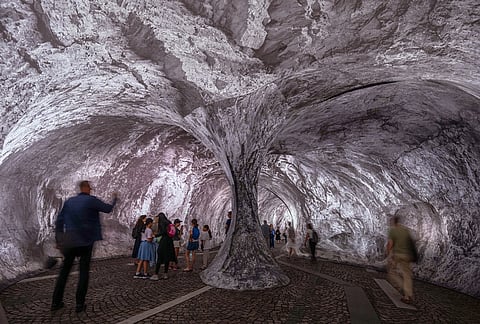 Visitors walk into the artwork "The Pont Neuf Cave" by French street artist JR on the Pont Neuf bridge, Tuesday, June 16, 2026, in Paris, open to the public from June 15 to 28.