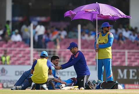 A physio puts cold towel around the neck of India's captain Shubman Gill as a teammate stands with an umbrella to beat the heat during the second ODI cricket match between India and Afghanistan in Lucknow.