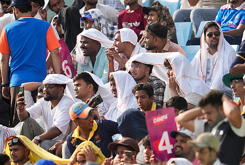 Fans cover their heads to beat the heat during the second ODI cricket match between India and Afghanistan in Lucknow.