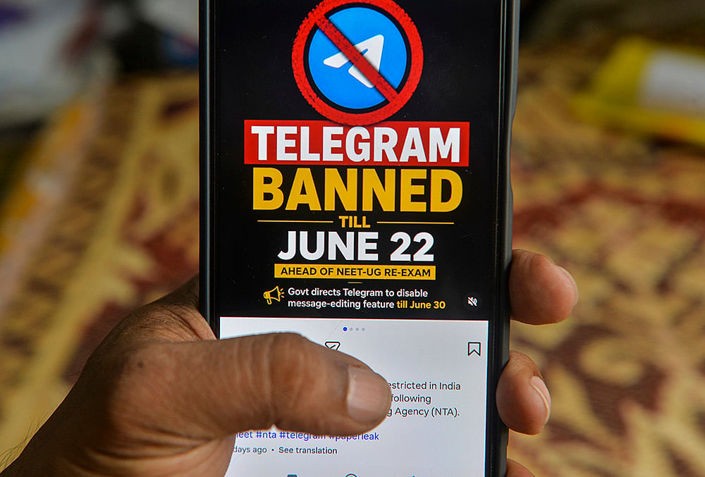 A man checks his mobile phone displaying information related to the temporary restriction on the messaging application Telegram ahead of the NEET-UG re-examination, in Siliguri, West Bengal. - | Photo: PTI