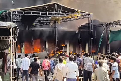 People gather at the site as flames and dark smoke billows after a massive fire broke out at Nimbahera fruit market, gutting four shops, in Chittorgarh district, Rajasthan.
