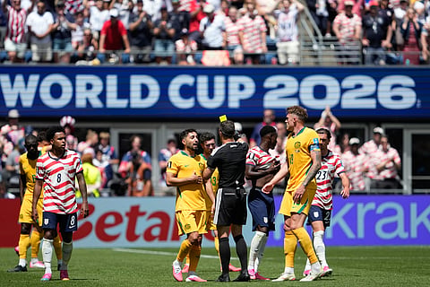 Referee Felix Zwayer, of Germany, a yellow card to Australia's Jacob Italiano, center, during the World Cup Group D soccer match between the United States and Australia in Seattle, Friday, June 19, 2026.