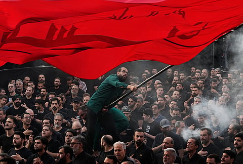 A man waves a religious flag as people beat their chests during a mourning ceremony in Tehran, Iran, ahead of Ashoura, which honors the 7th-century martyrdom of the Prophet Muhammad's grandson, Hussein, who was killed in a battle in Karbala in present-day Iraq. 
