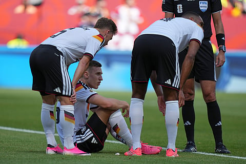 Germany's Nico Schlotterbeck, centre, waits to receive treatment following an injury during the World Cup Group E soccer match.
