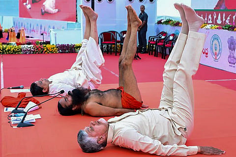 In this image received on June 21, 2026, From right, Andhra Pradesh Chief Minister N Chandrababu Naidu, Yoga guru Baba Ramdev and Patanjali Ayurved Managing Director Acharya Balkrishna perform yoga during the International Day of Yoga celebrations, in Vijayawada. ()(PTI06_21_2026_000232B)