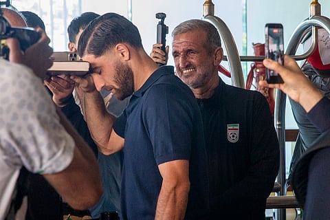 Iran national soccer team member Alireza Jahanbakhsh touches his forehead to the Quran while Mehdi Malekabad