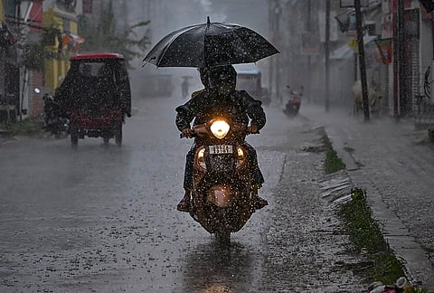 Commuters move on a two-wheeler amid rain, in Nadia.