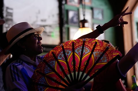 An Argentina soccer fan, keeping cool with a fan, parties with Scotland soccer fans from the Tartan Army in Miami's Little Havana neighborhood, Monday, June 22, 2026