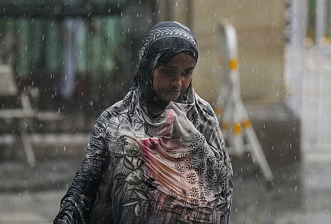 A woman walks amid rain, in Kolkata.