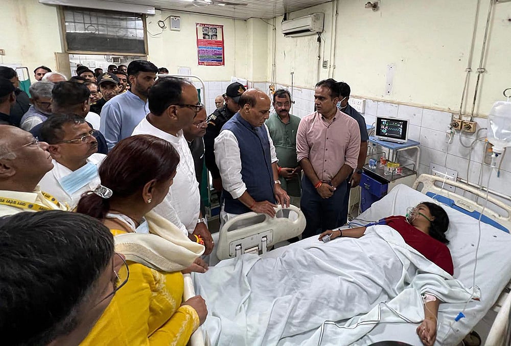 Union Defence Minister Rajnath Singh, accompanied with Uttar Pradesh Deputy Chief Minister Brajesh Pathak, interacts with an injured victim during his visit to King George's Medical University (KGMU) after a fire engulfed a three-story commercial building in a posh neighbourhood resulting in the deaths of 15 people, including students, and injuring seven others, in Lucknow, Uttar Pradesh. - | Photo: PTI
