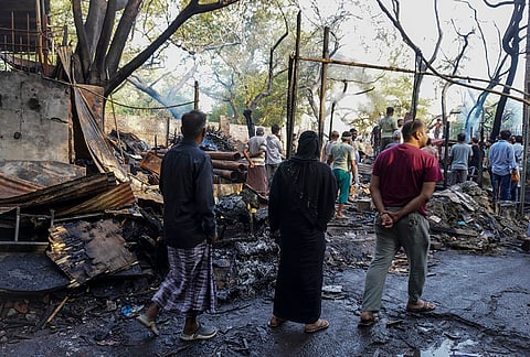 Charred remains at the site as locals gather after a fire broke out in slums behind Maulana Azad Medical College in Balmiki Basti area of Takia Kale Khan, in New Delhi.