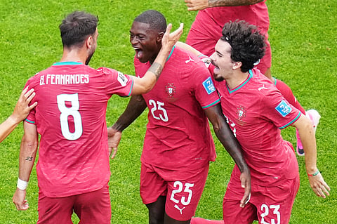 Portugal's Nuno Mendes (25) reacts with teammates Portugal's Bruno Fernandes (8) and Portugal's Vitinha (23) celebrate a goal.