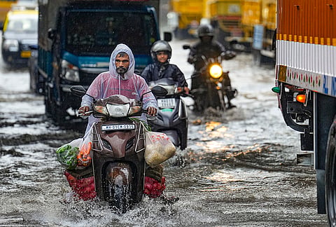 Commuters navigate a waterlogged road after heavy rainfall inundates several parts of the city, in Mumbai, Maharashtra.