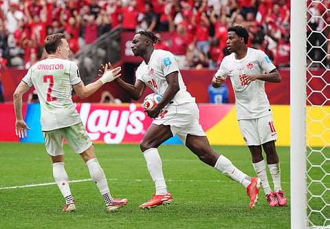 Canada's Promise David (24) retrieves the ball and celebrates his goal with Alistair Johnston (2) and Jonathan David (10) during the World Cup Group B soccer match between Switzerland and Canada in Vancouver, British Columbia, Wednesday, June 24, 2026.