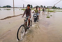 Day In Pics: June 24, 2026 | Photo: PTI : People wade through a waterlogged road at Morisutipam village in Morigaon district, Assam.