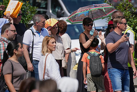 People wait in a line to enter the Vatican Museums as temperatures reach record highs, in Rome.