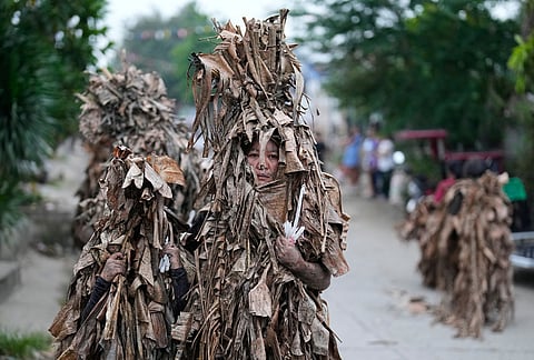 Catholic devotees covered in mud and dried banana leaves join the mud people festival on the feast day of Saint John the Baptist at Bibiclat, Nueva Ecija province, northern Philippines.