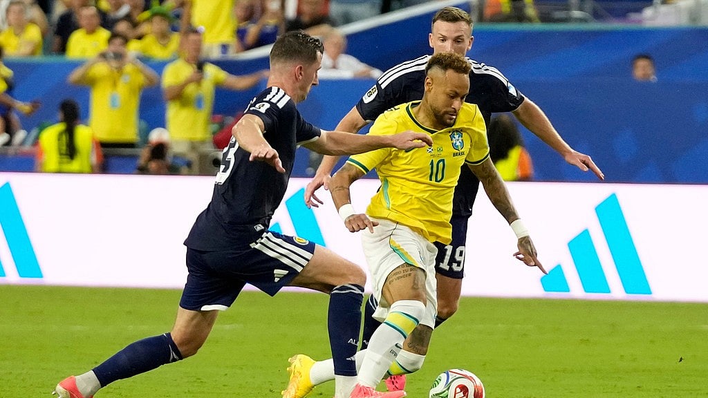 Brazil's Neymar (10) challenges for the ball with Scotland's Kenny McLean (23) and Lewis Ferguson (19) during the World Cup Group C soccer match between Scotland and Brazil in Miami Gardens. - Lynne Sladky/AP