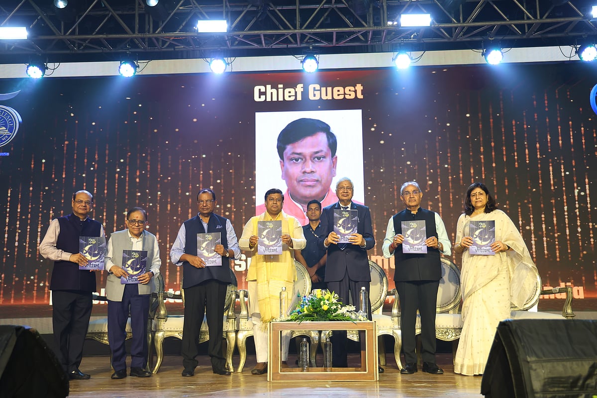 Dignitaries holding up a magazine on stage at The Heritage School Silver Jubilee event