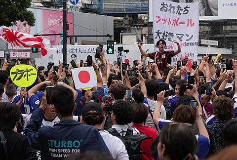 Fans react after a World Cup Group F soccer match in the United States between Japan and Sweden as they gather in Tokyo's Shibuya Crossing.
